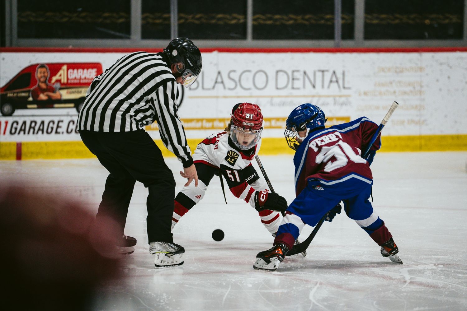 Close-up action shot of hockey players battling for puck control on ice.