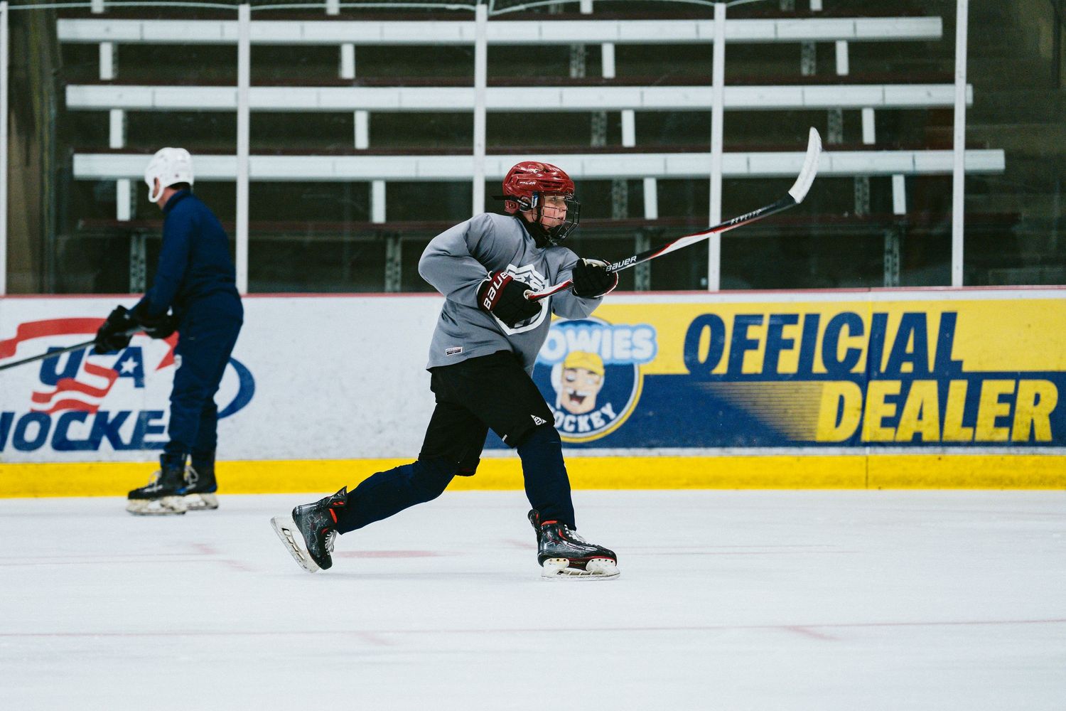 Hockey player in red helmet takes a shot on ice rink during practice.