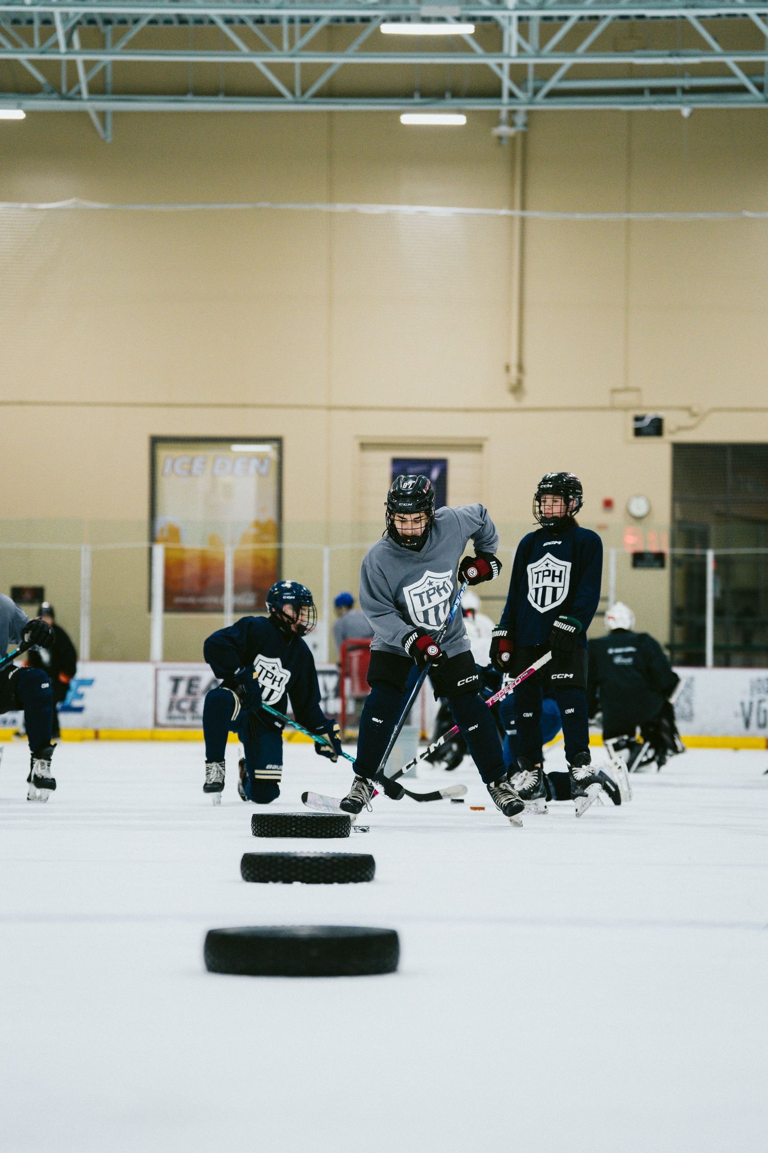 Youth hockey players practice skating drills on indoor ice rink during team training session.