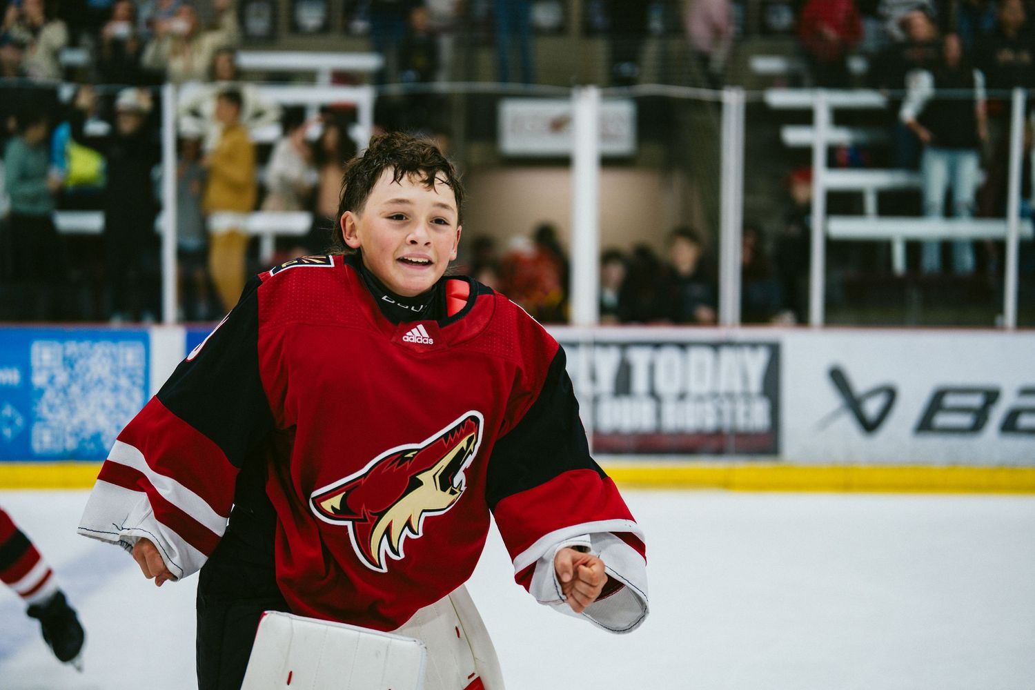 Hockey players in red Arizona Coyotes jerseys move across the ice during a game.