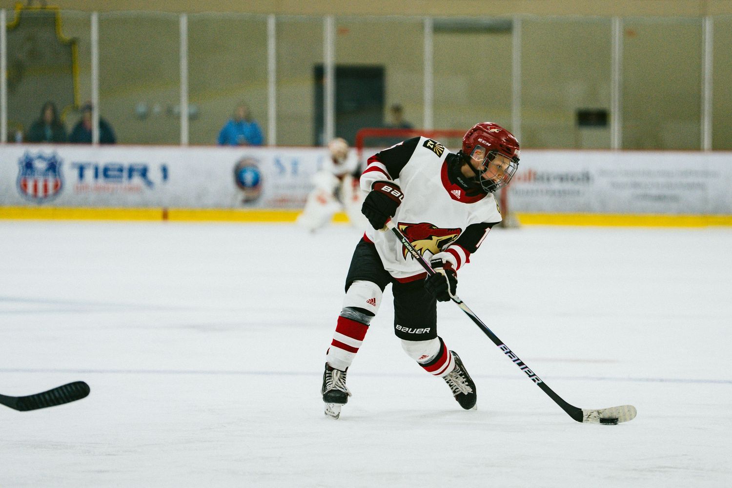 Hockey players practice skating drills during training session on indoor rink.