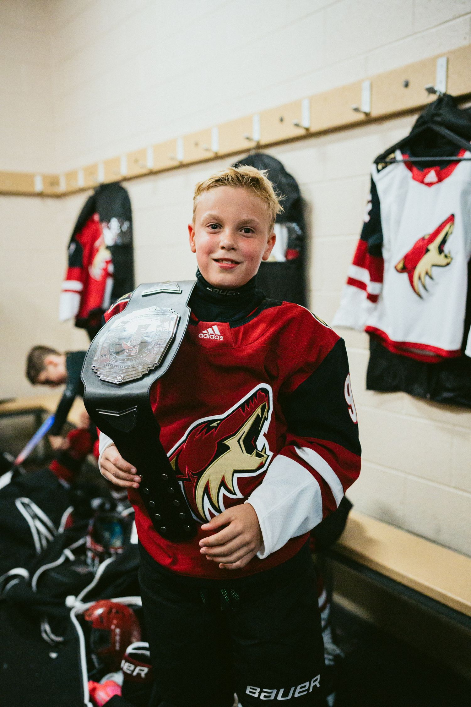 Hockey gear and equipment in locker room with red and black jerseys.