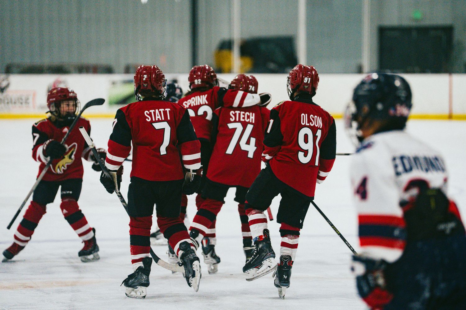 Youth hockey players in red jerseys skate in formation during a game.