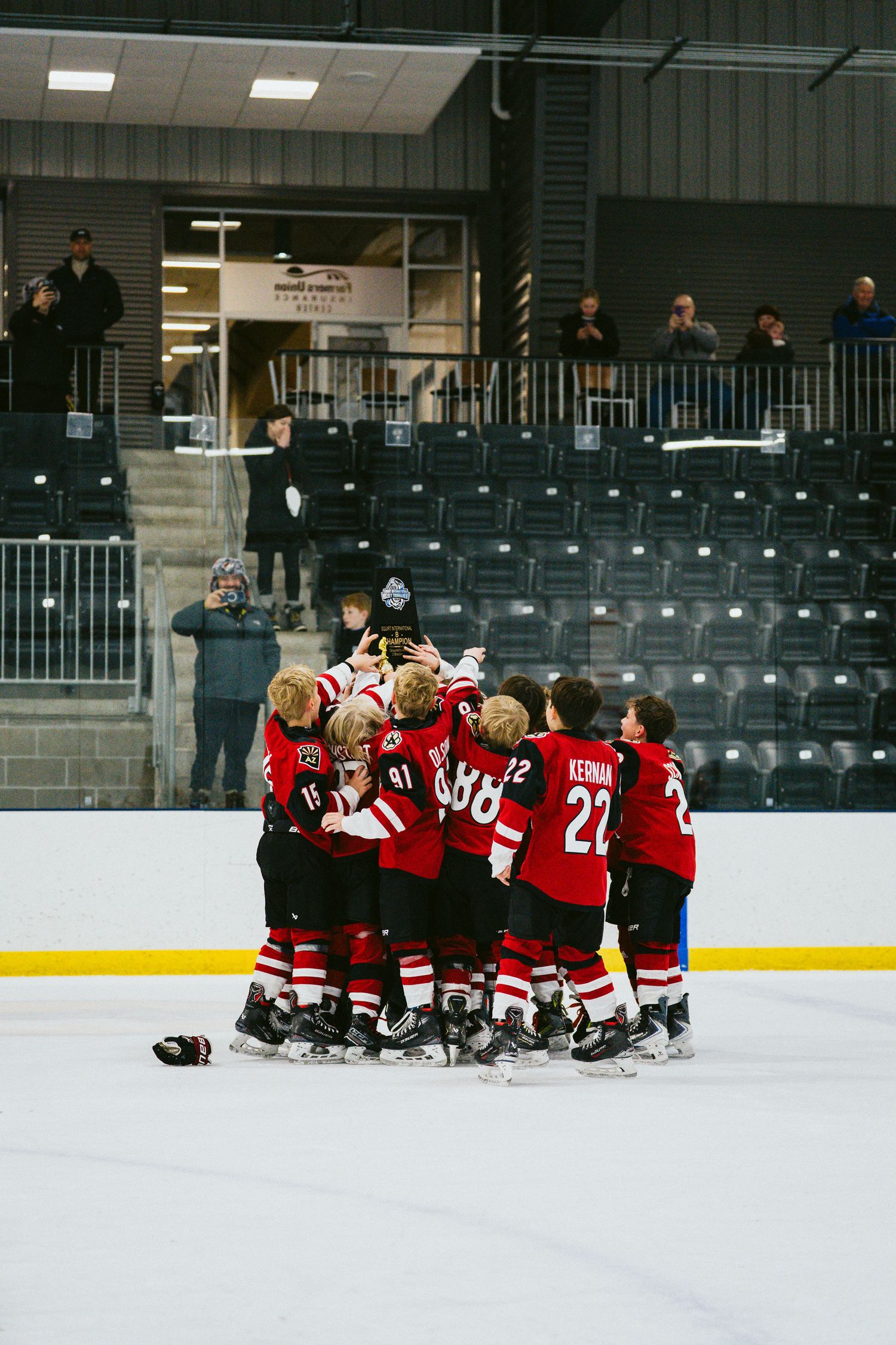 Youth hockey team huddled together on ice during practice at indoor arena.