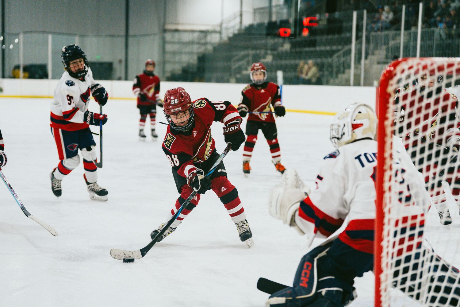 Hockey game action showing players from both teams near the goal net.