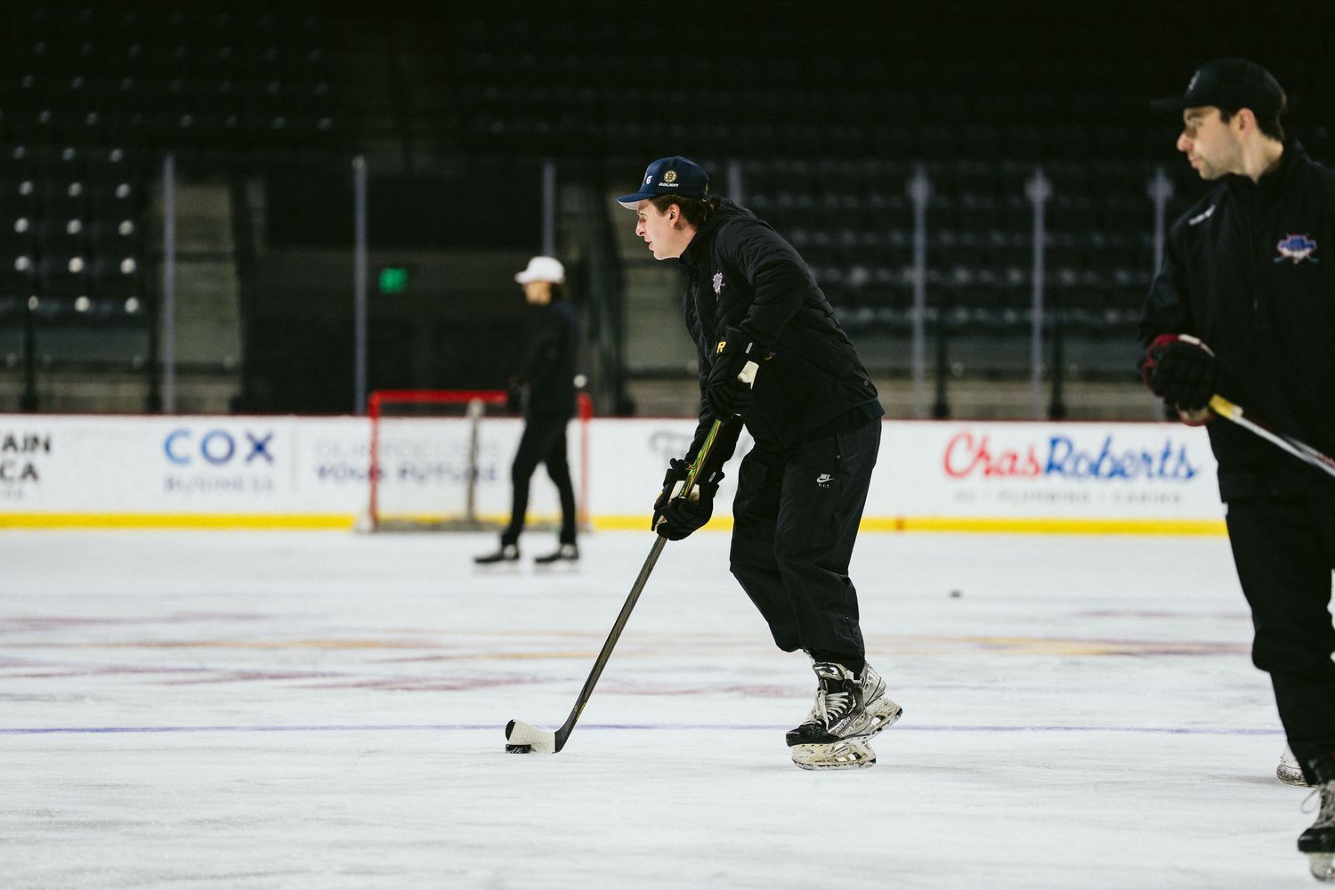 Hockey player handling puck during skating drill at indoor arena practice session.