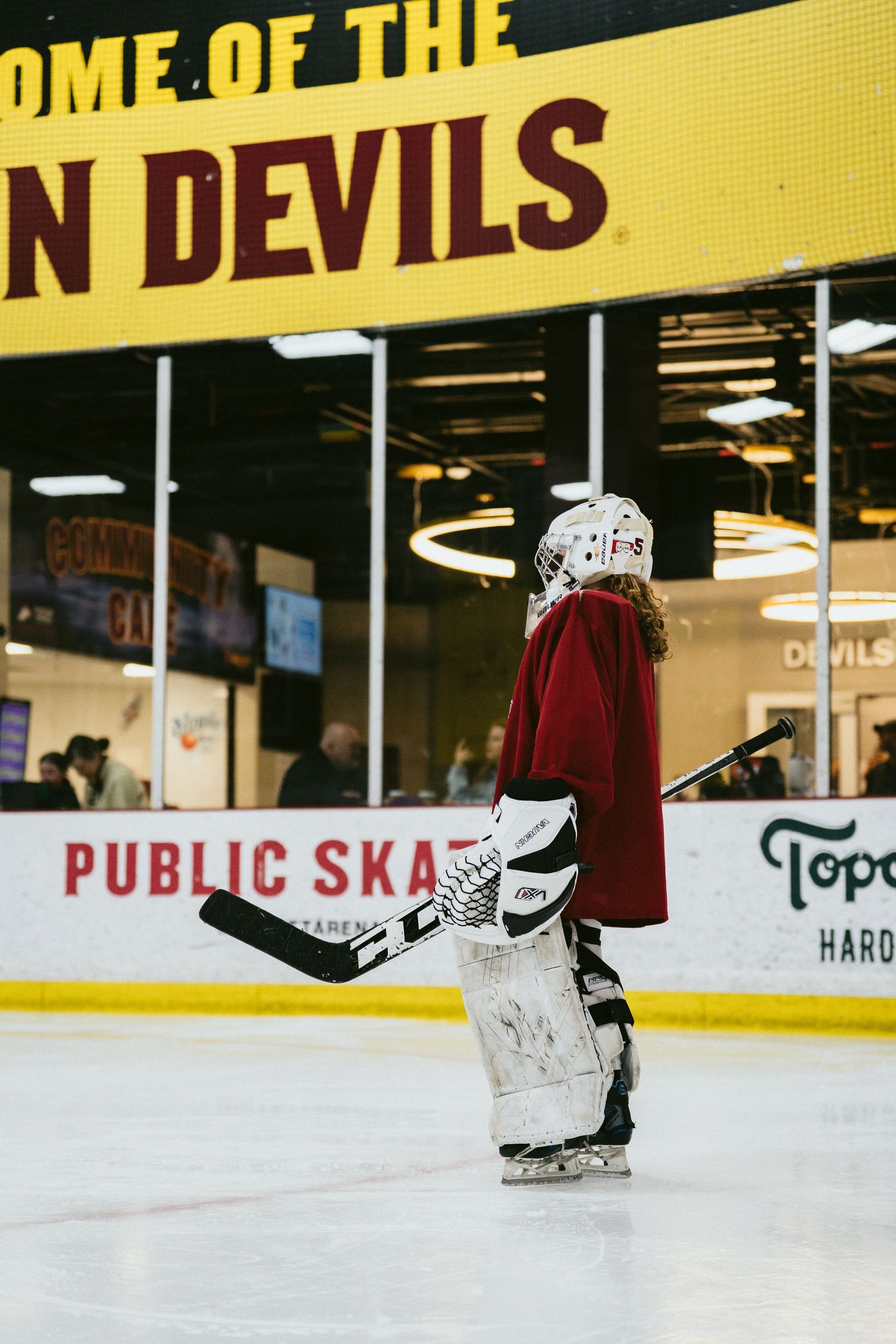 Young hockey goalie in full gear stands on ice rink at New Jersey Devils public skating session.