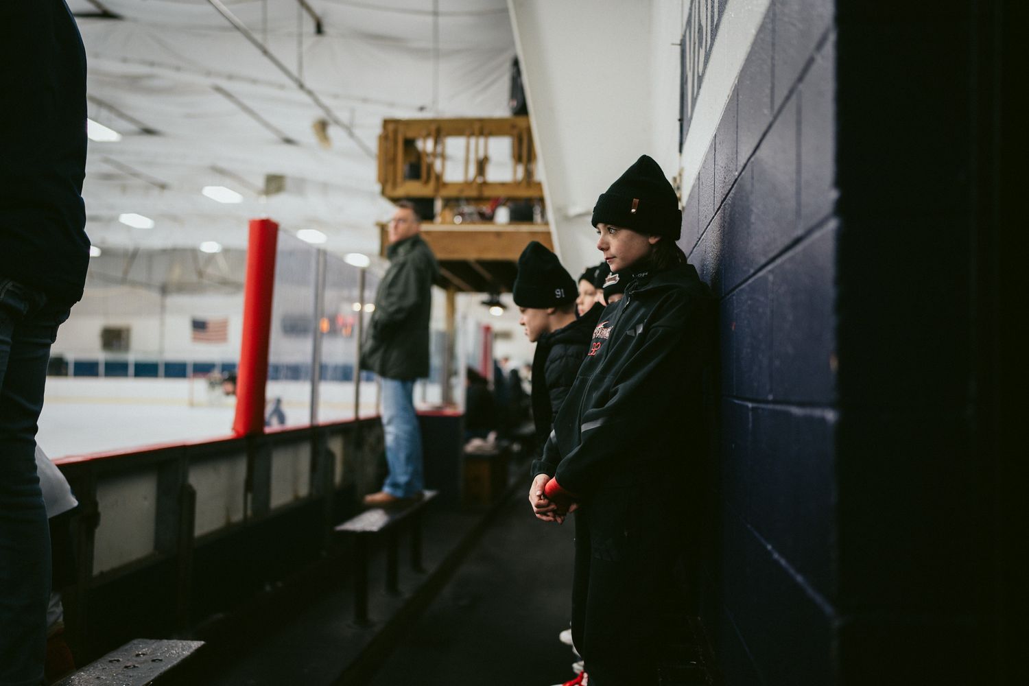 Dark hallway scene inside a hockey arena with equipment visible.