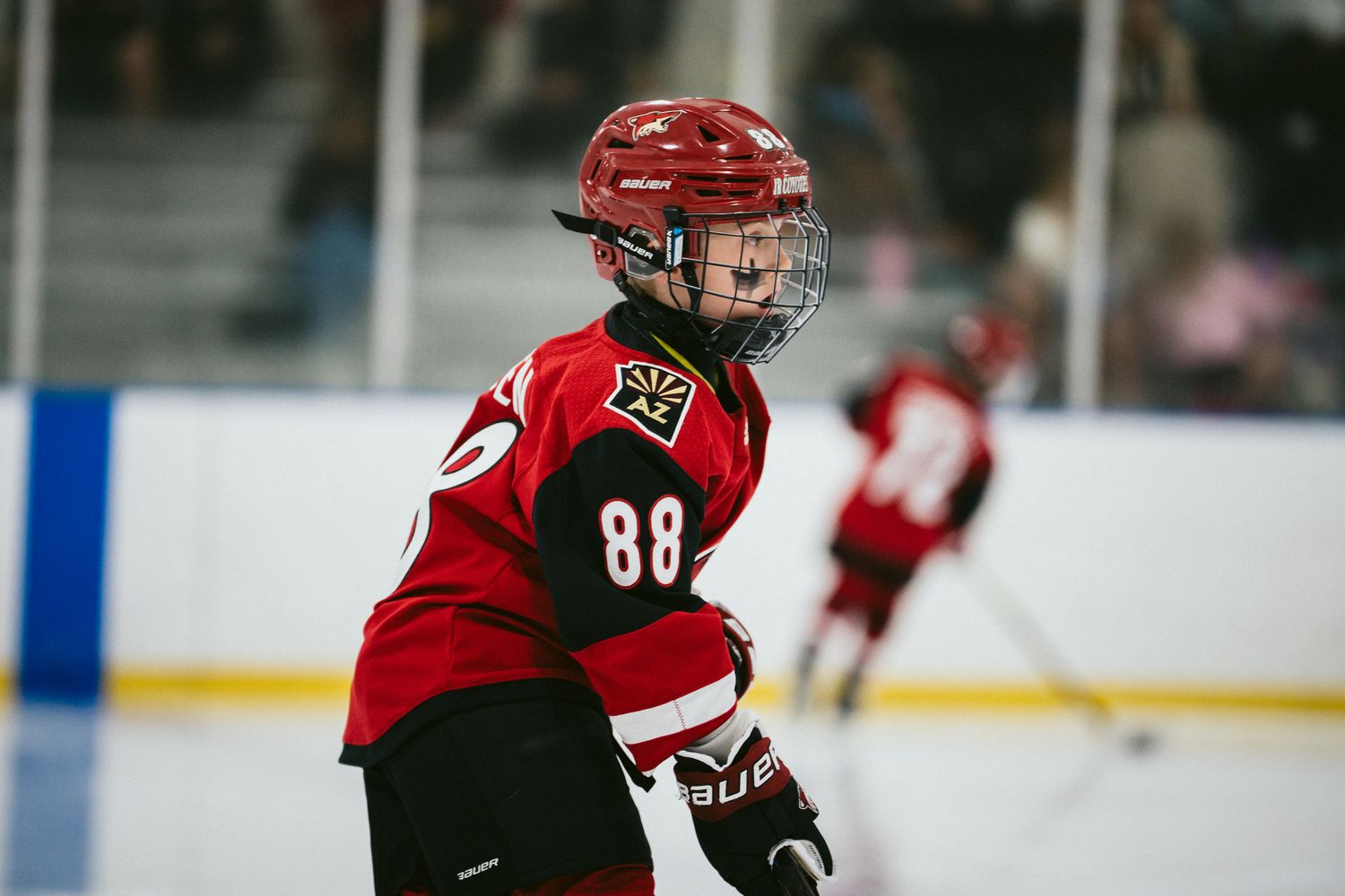 Youth hockey player wearing number 88 red jersey skating during game.