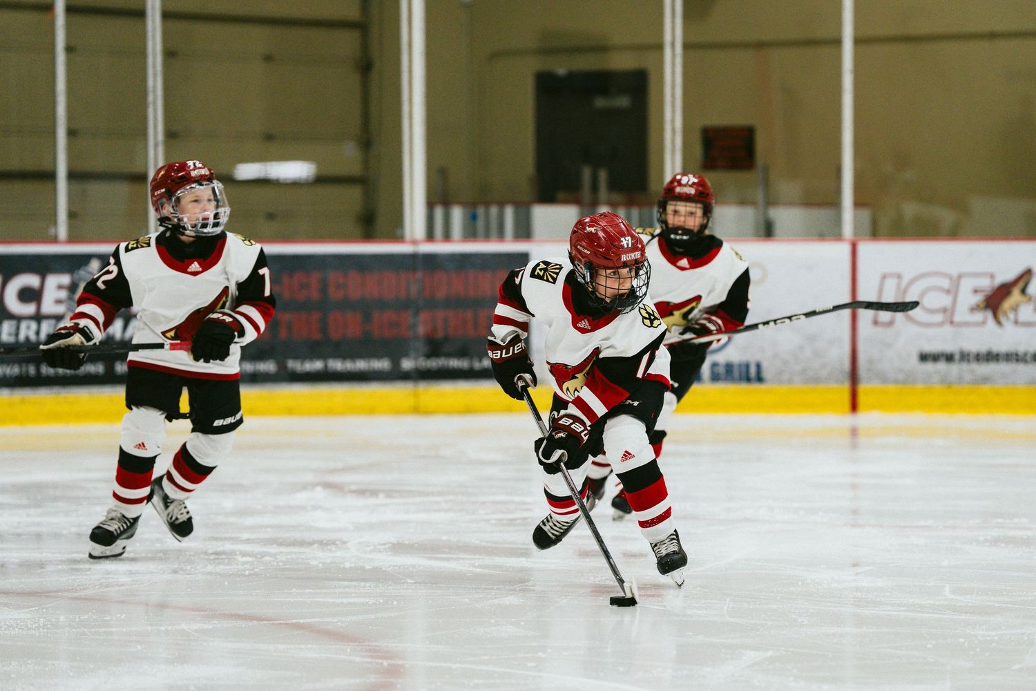 Hockey player in red and white uniform skates with the puck during an ice hockey game.