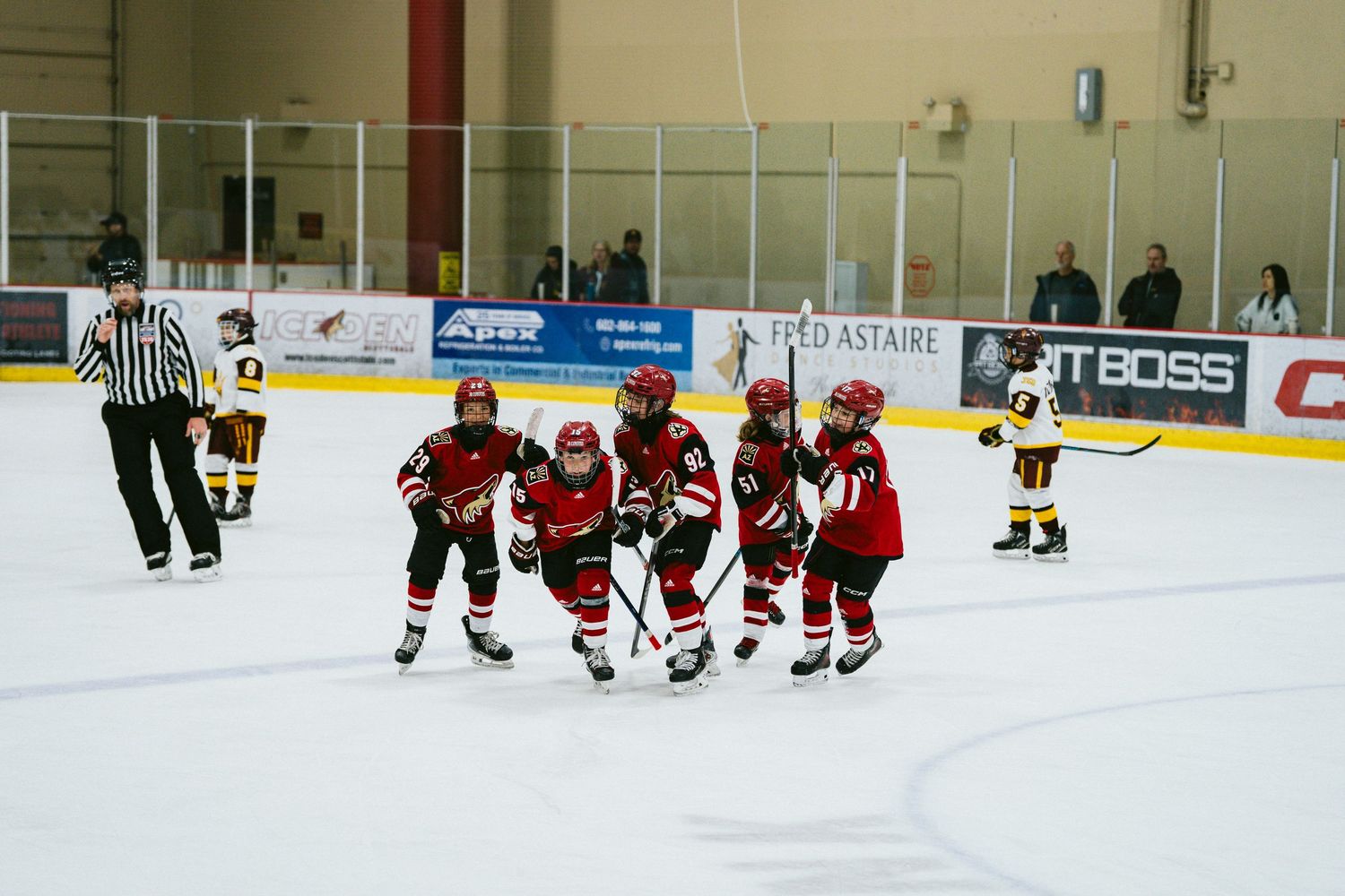 Young hockey players practice skating drills on an indoor ice rink during a youth training session.