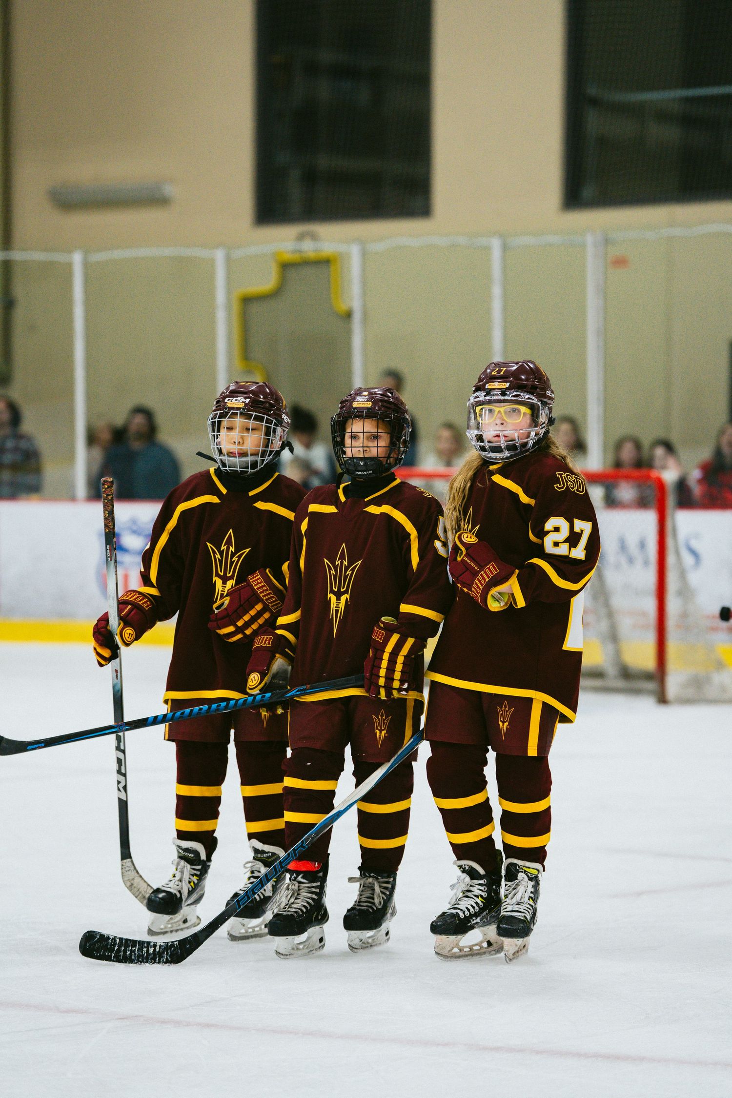 Young hockey players in brown and gold uniforms line up on the ice rink.