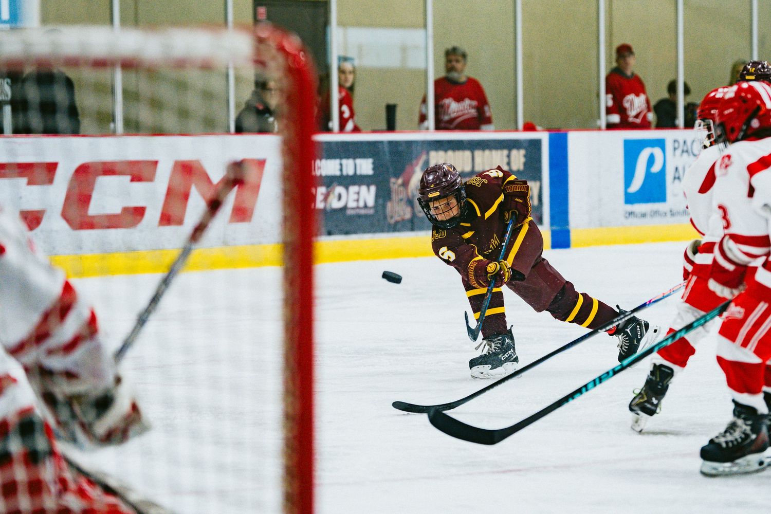 Close-up view of hockey players' skates and sticks battling for puck control on ice.