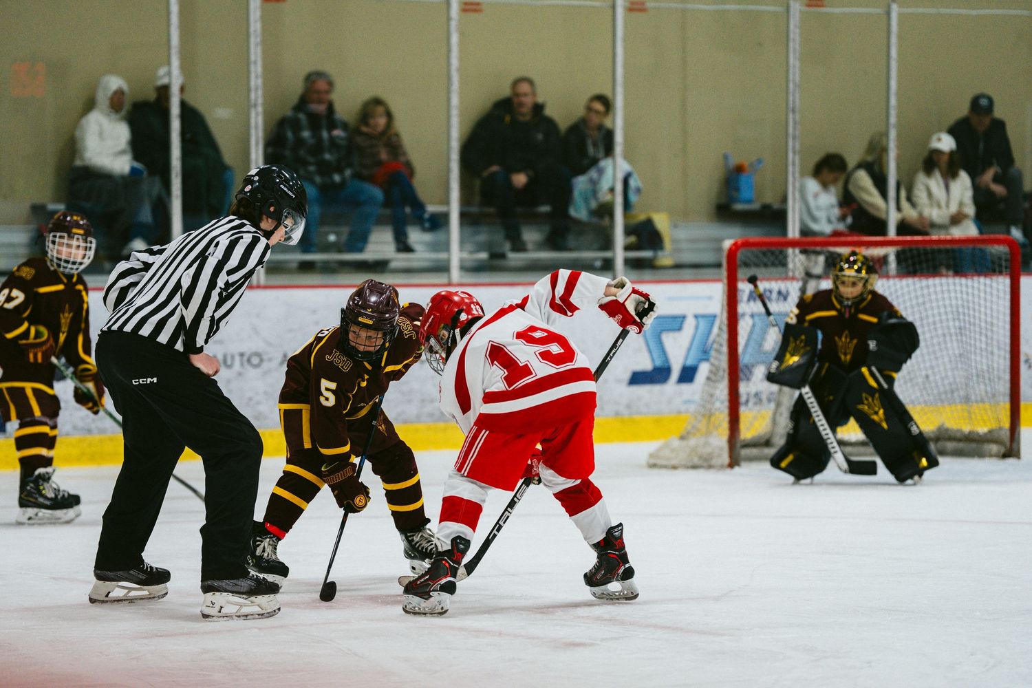 Wide angle shot of youth hockey game showing players from both teams spread across the ice.
