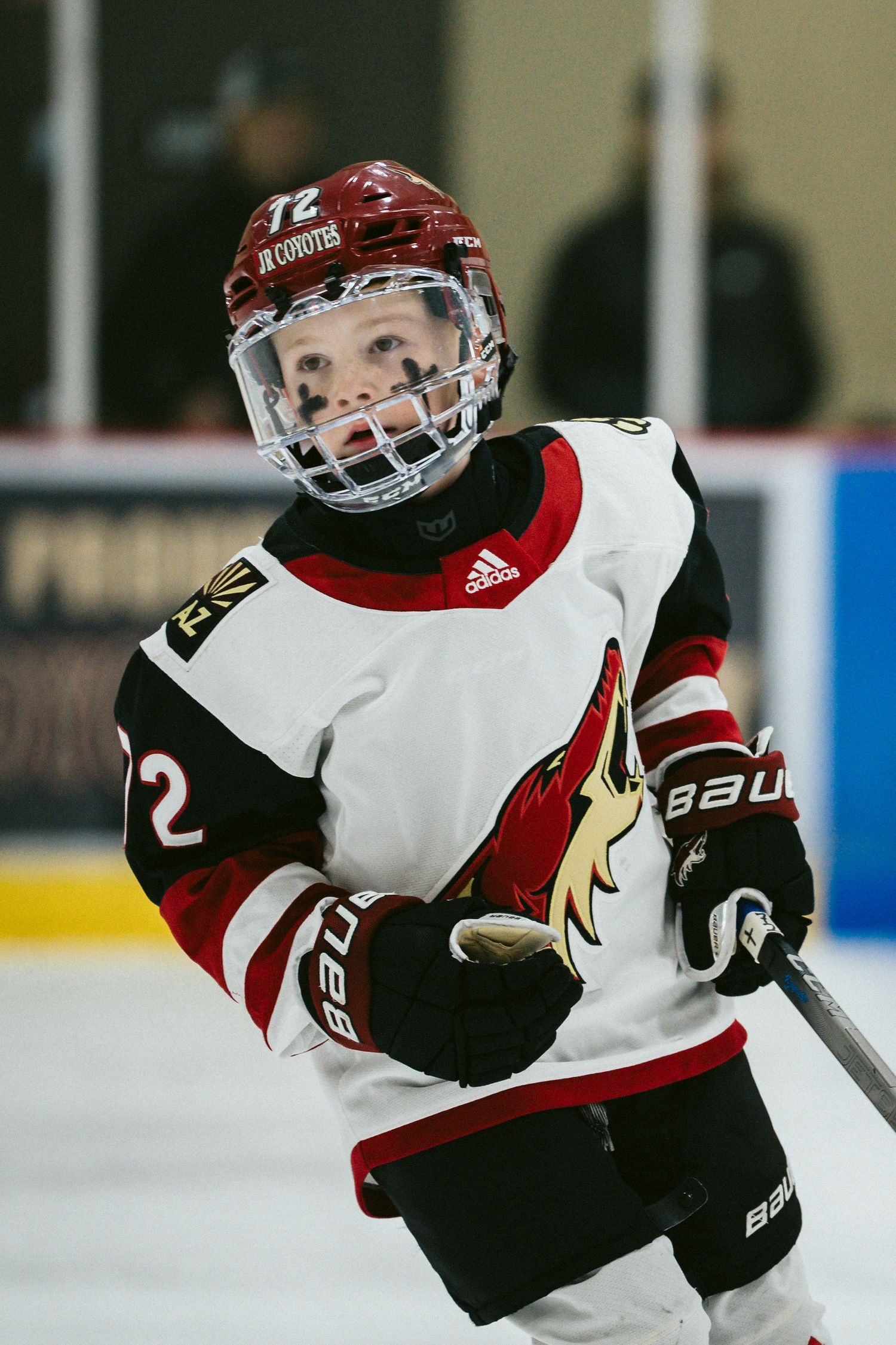 Hockey player in Arizona Coyotes jersey skating with puck during game.