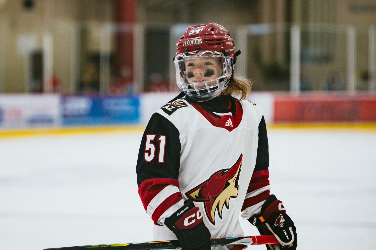 Hockey player in white Coyotes jersey number 51 on ice during game.