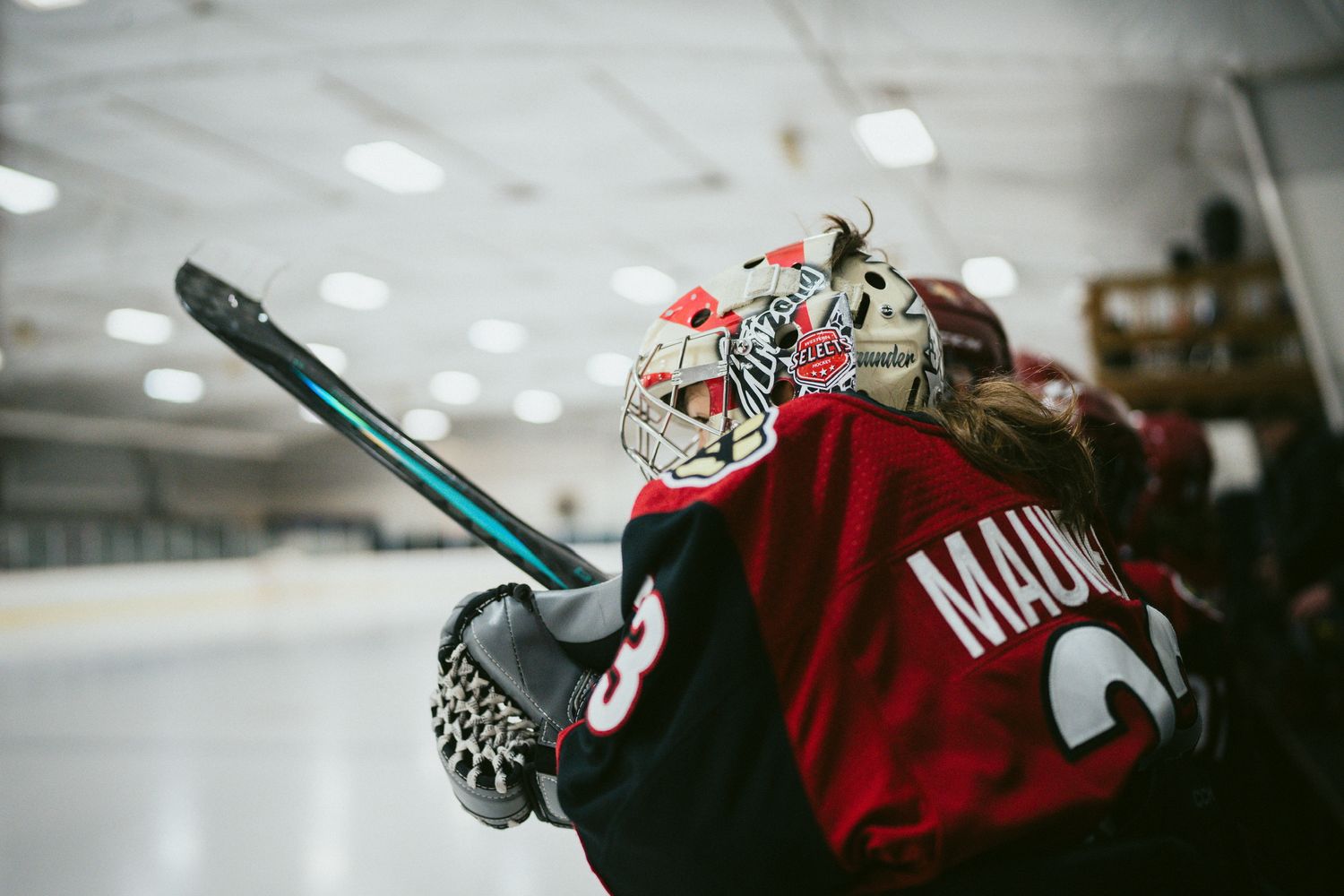 Close-up of hockey equipment and red jersey on the ice.