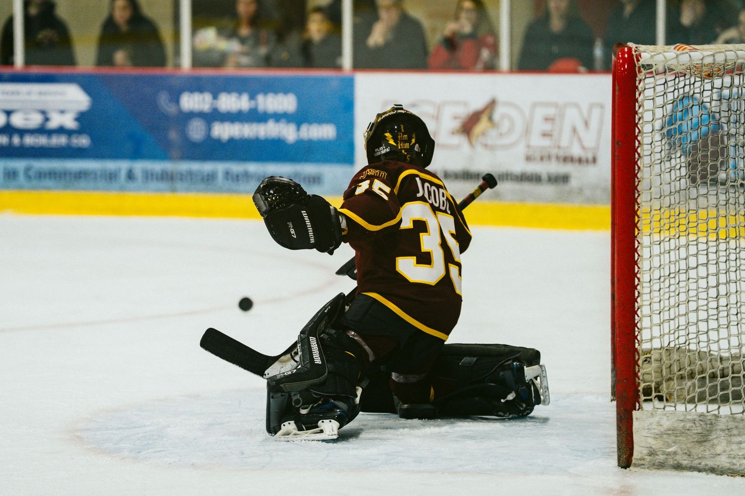 A goalie makes a diving save attempt during a hockey game.