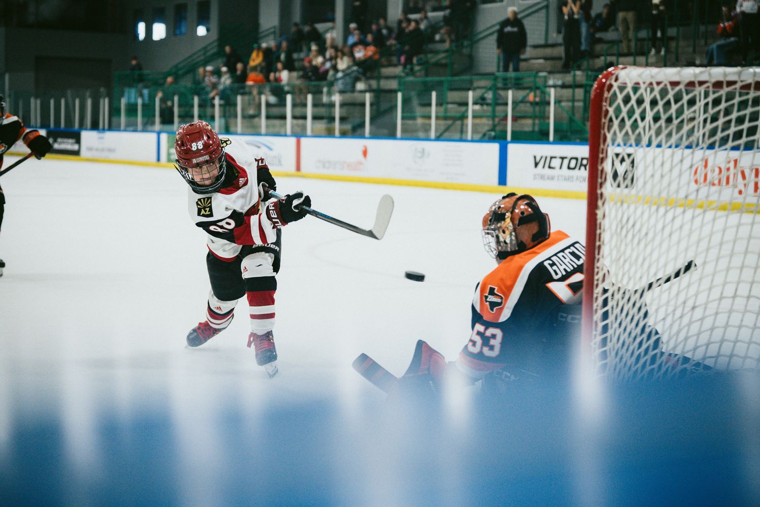 Wide angle view of a hockey game showing players and goal net on ice rink.