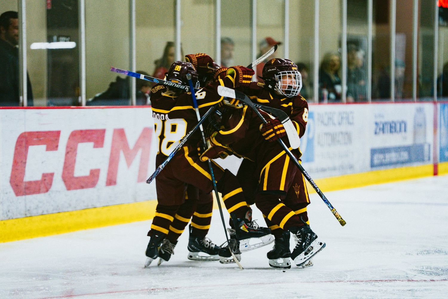 Wide view of a hockey rink showing players in black and gold uniforms during gameplay.