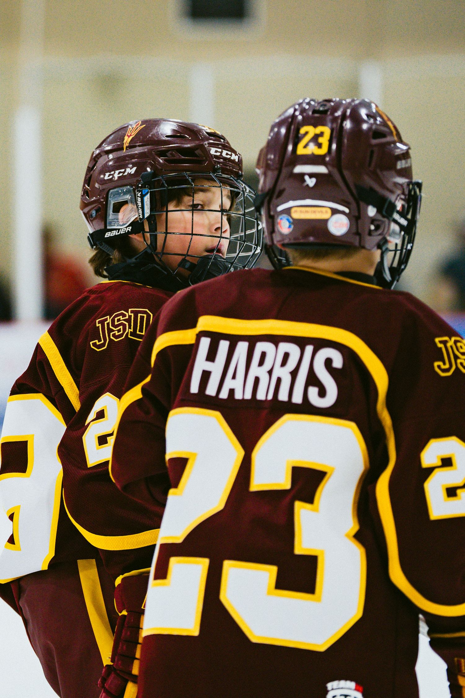 Row of hockey players in brown jerseys with yellow numbers line up on the bench.