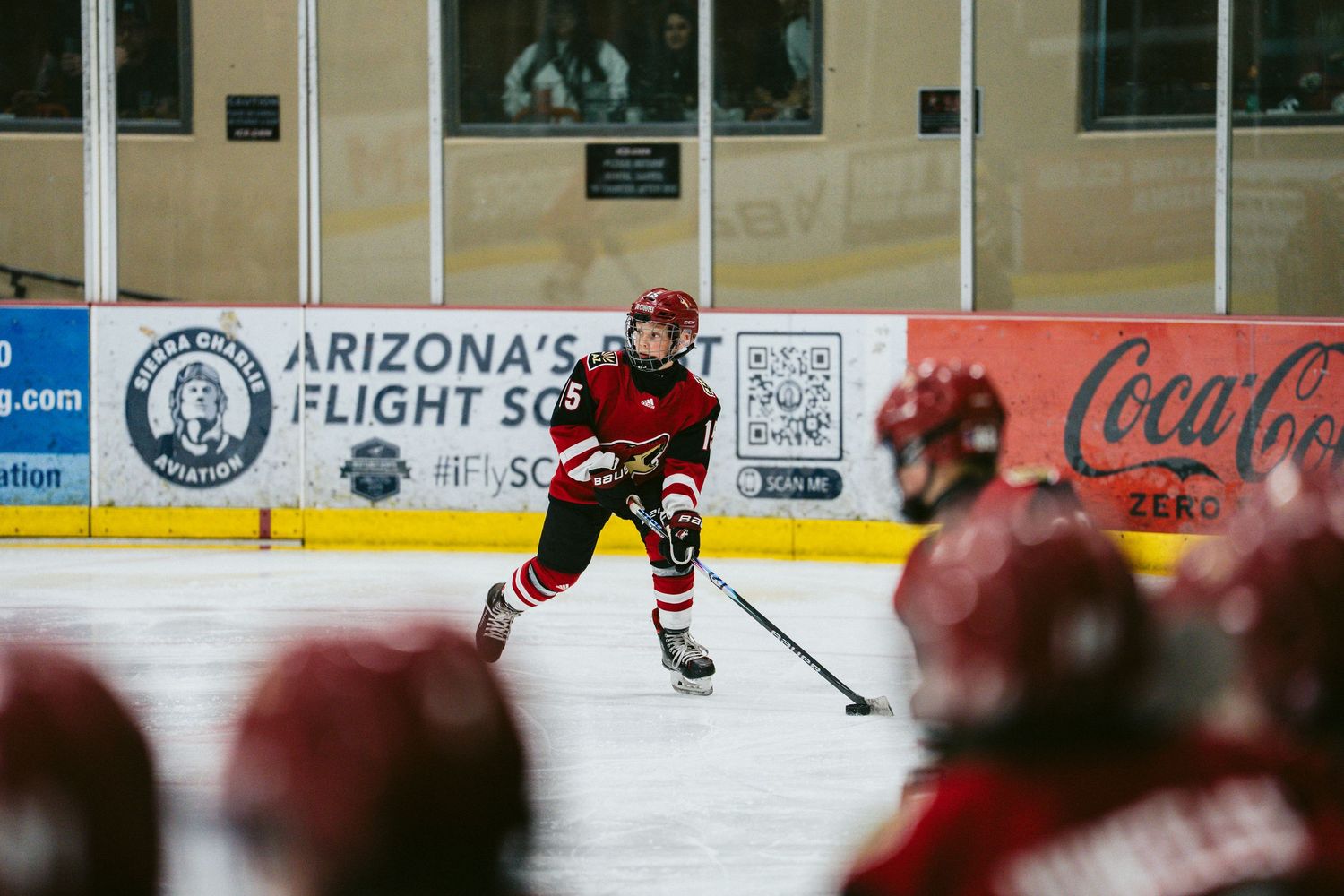 Hockey players in red uniforms spread across the ice during a practice session.