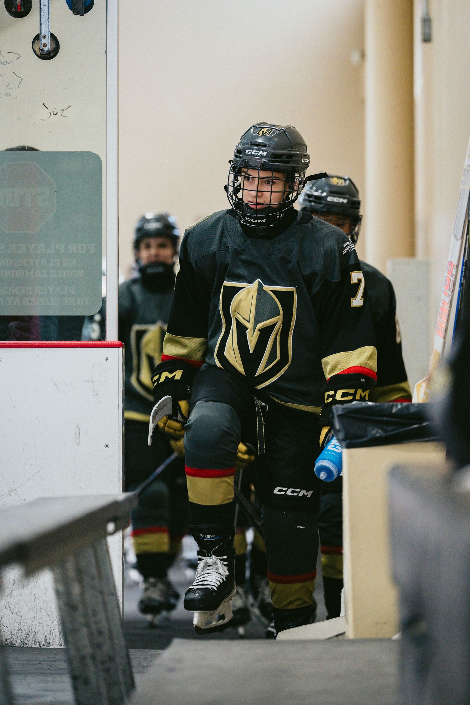 Hockey players in black and gold uniforms wait in the tunnel before taking the ice.