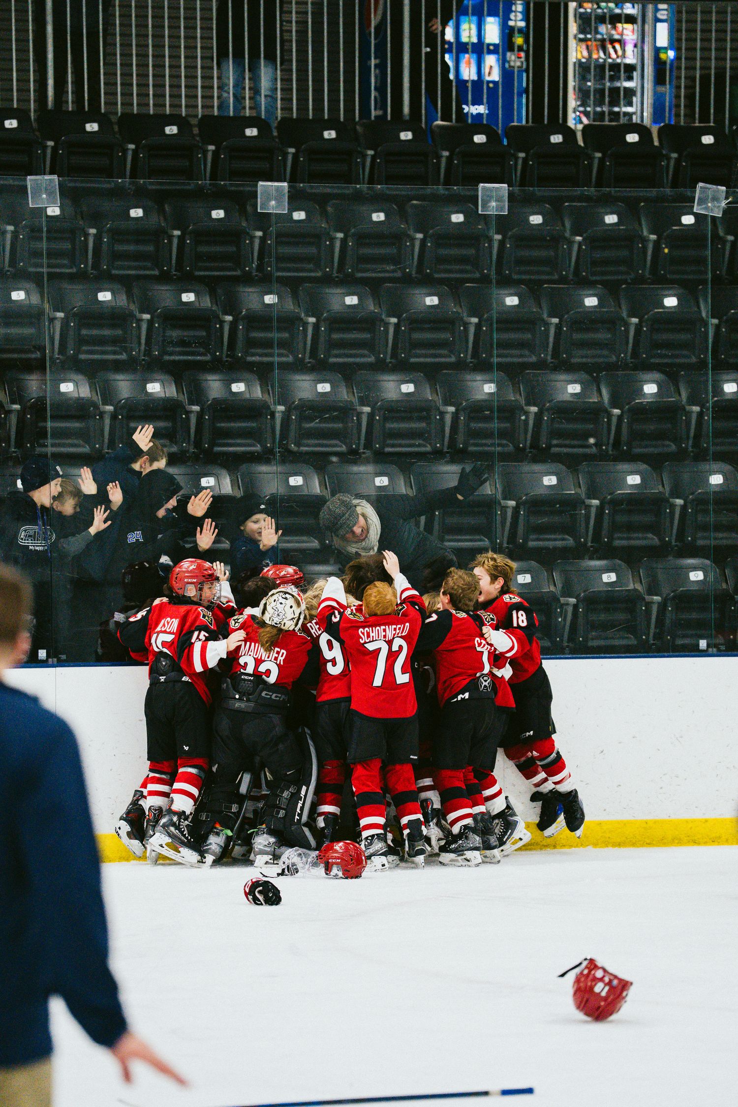 Hockey team in red uniforms celebrating together on the ice rink.