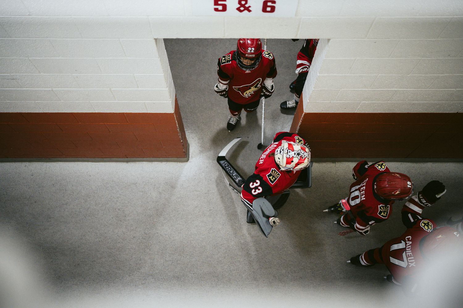 Hockey players in red uniforms viewed from above during practice.