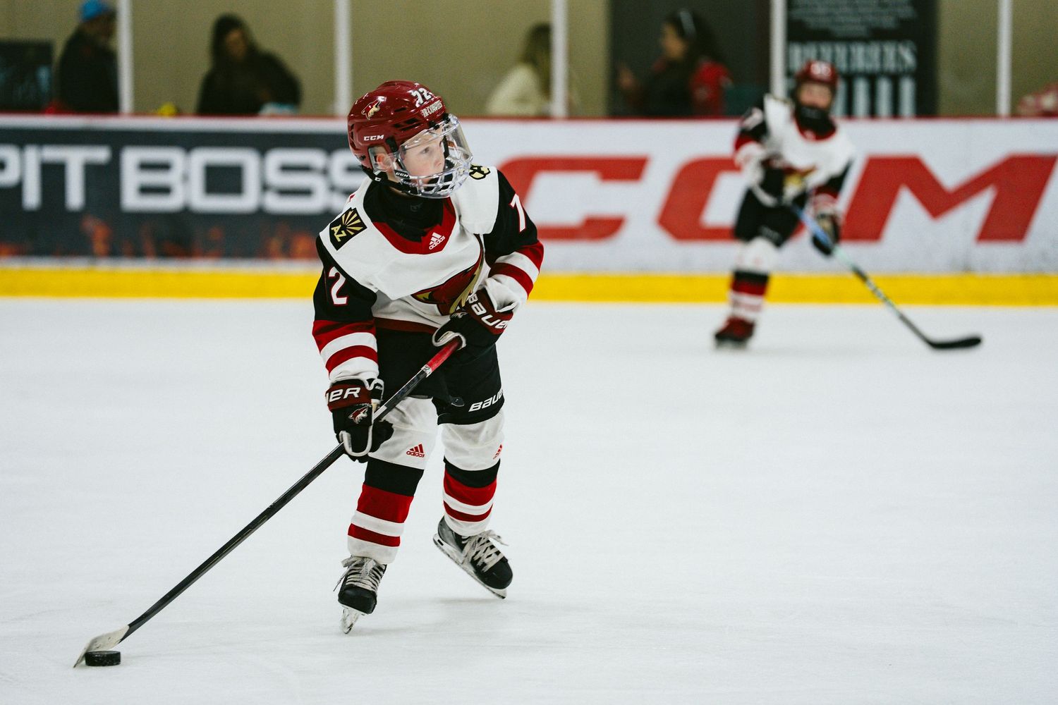 Ice hockey player in a white and red uniform skates with the puck during a game.