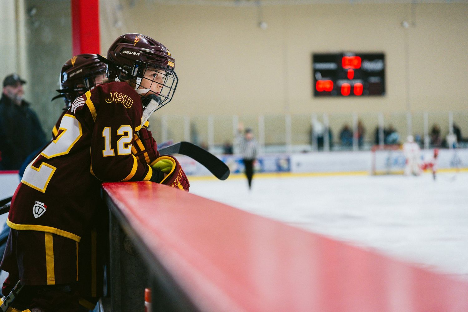 Hockey players in dark uniforms skate across the ice during a competitive game.