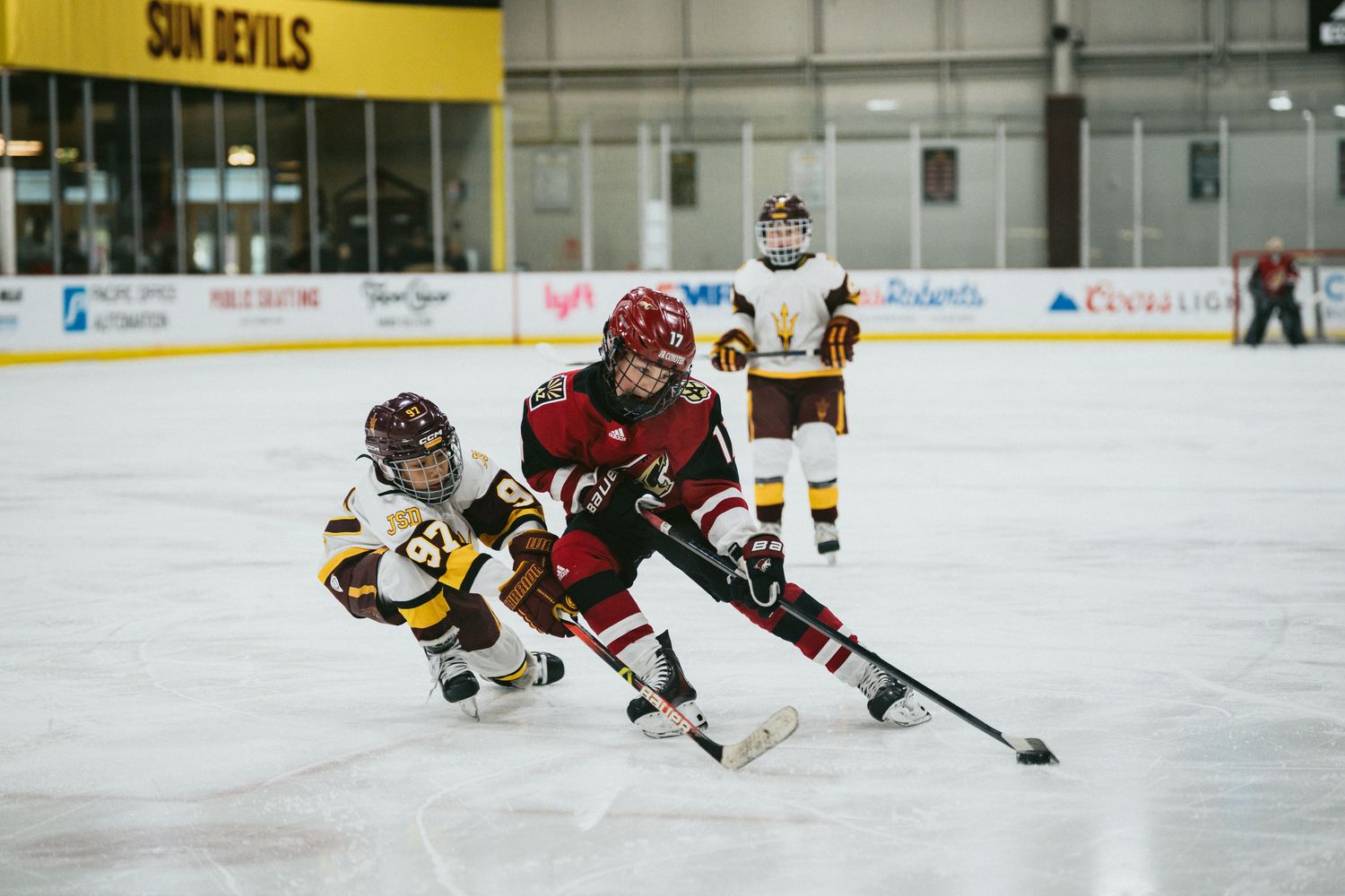 Hockey players from opposing teams competing for puck control on ice.