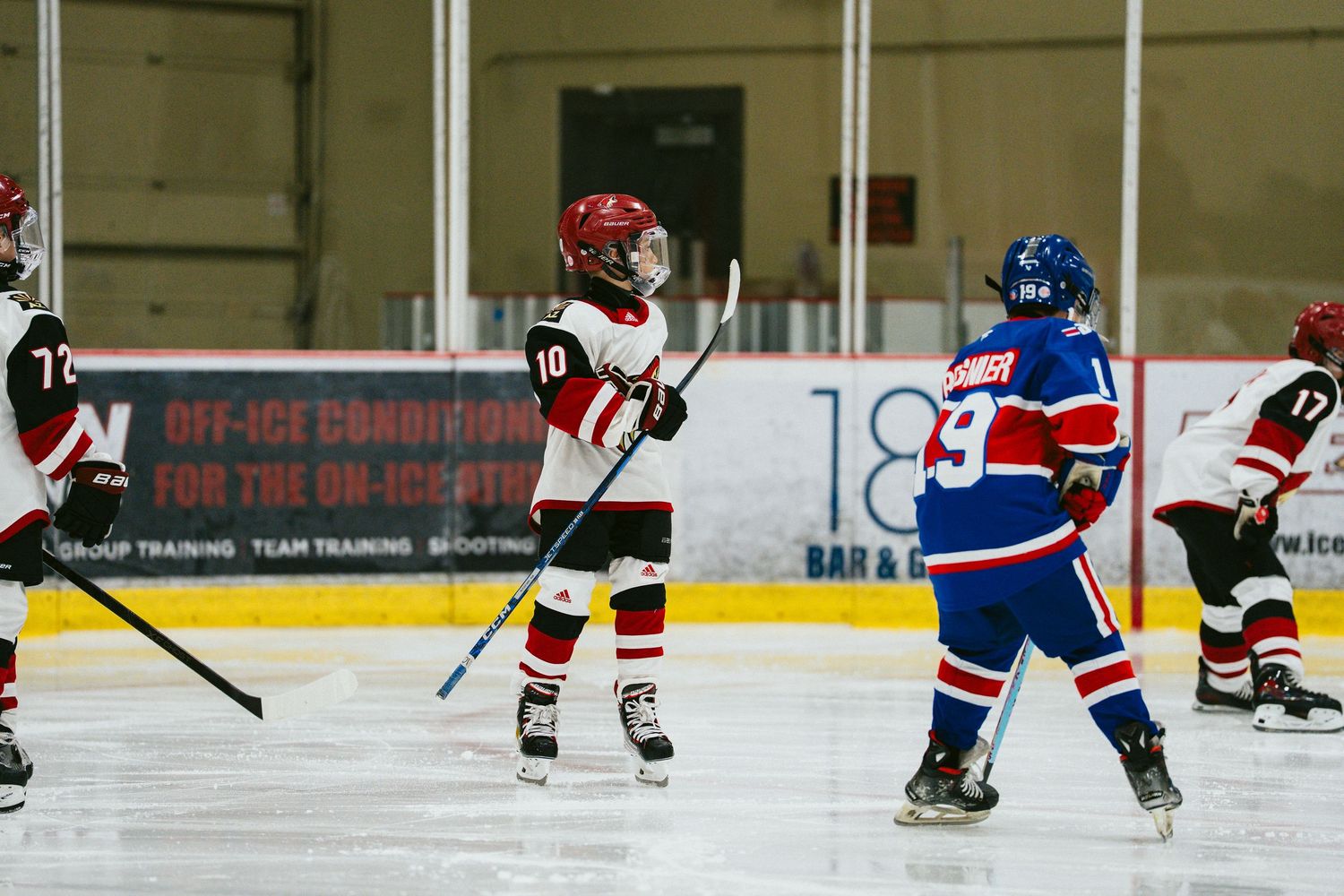 Hockey players spread across the ice rink during a competitive game.