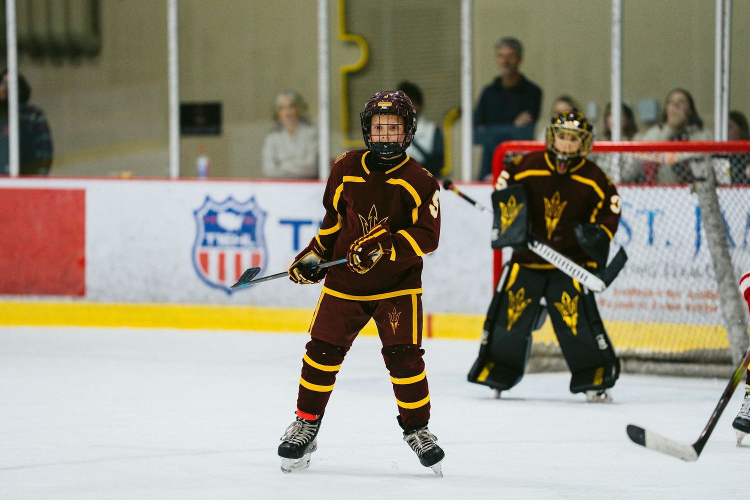 Hockey players in dark uniforms skating on ice during a competitive match.