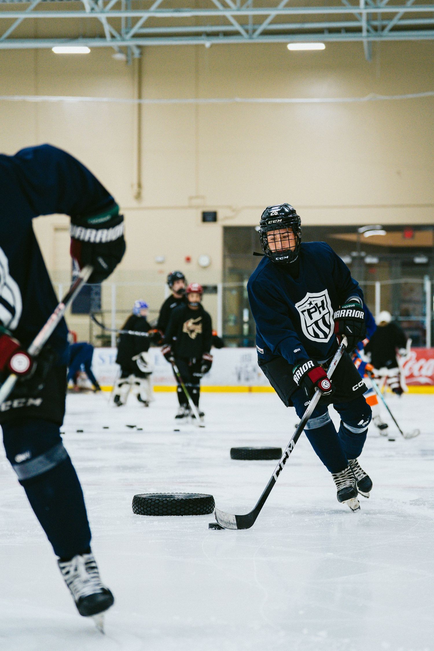 Youth hockey player controls puck during competitive ice hockey practice drill at indoor rink.