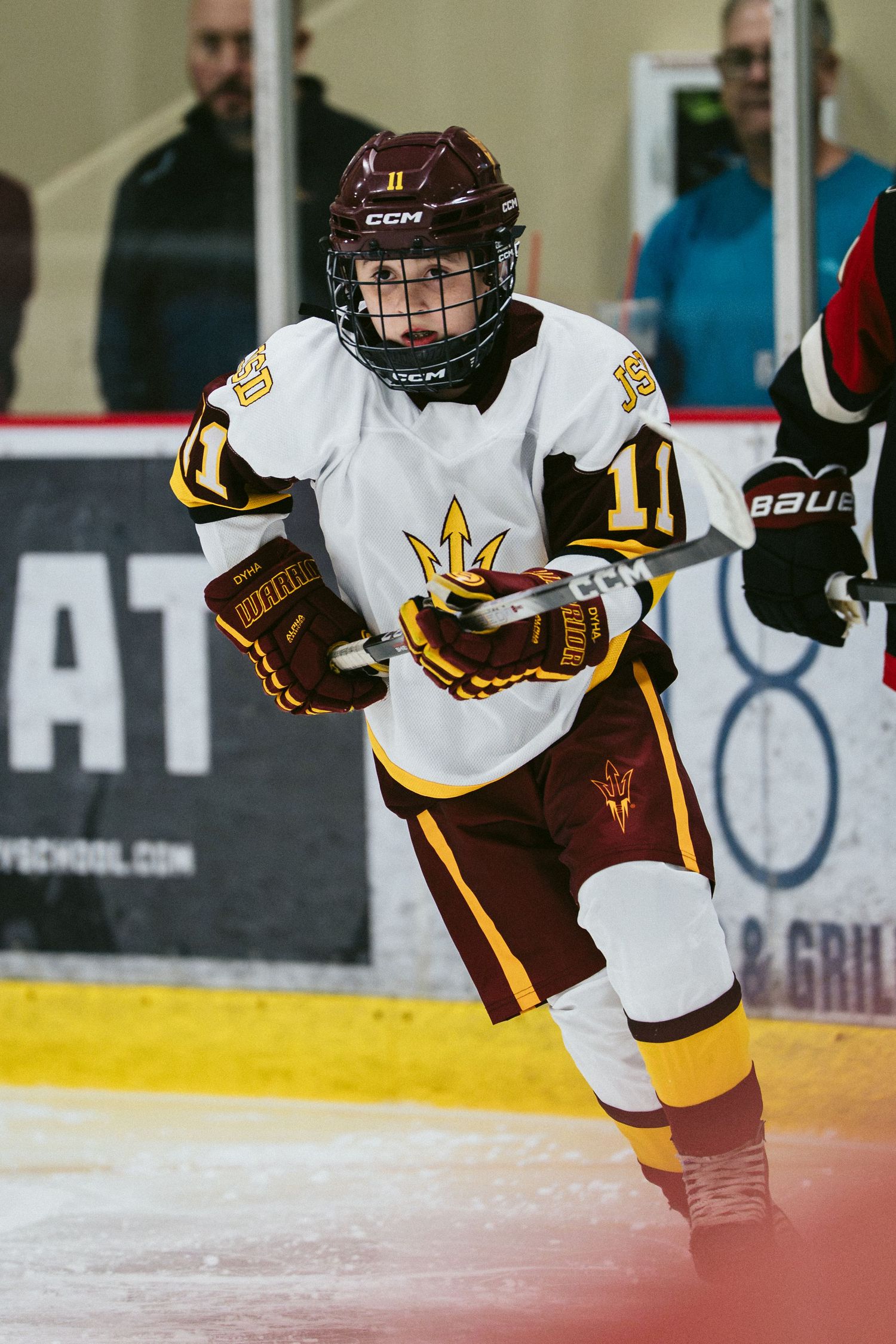 Arizona State Sun Devils hockey player in white and maroon uniform skating on ice during a college hockey game.