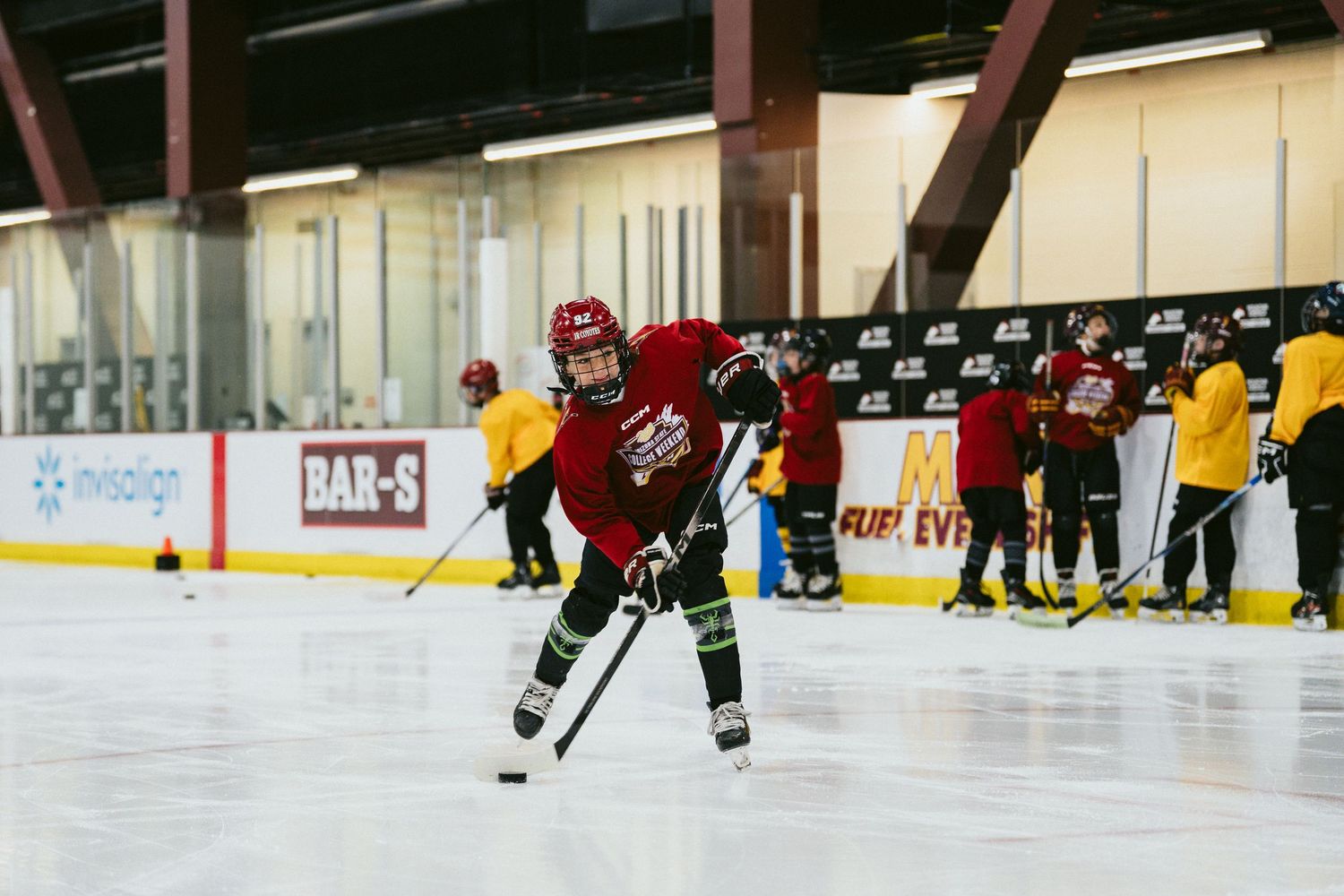 Youth hockey players practice skating drills on an indoor ice rink during a hockey training camp session.