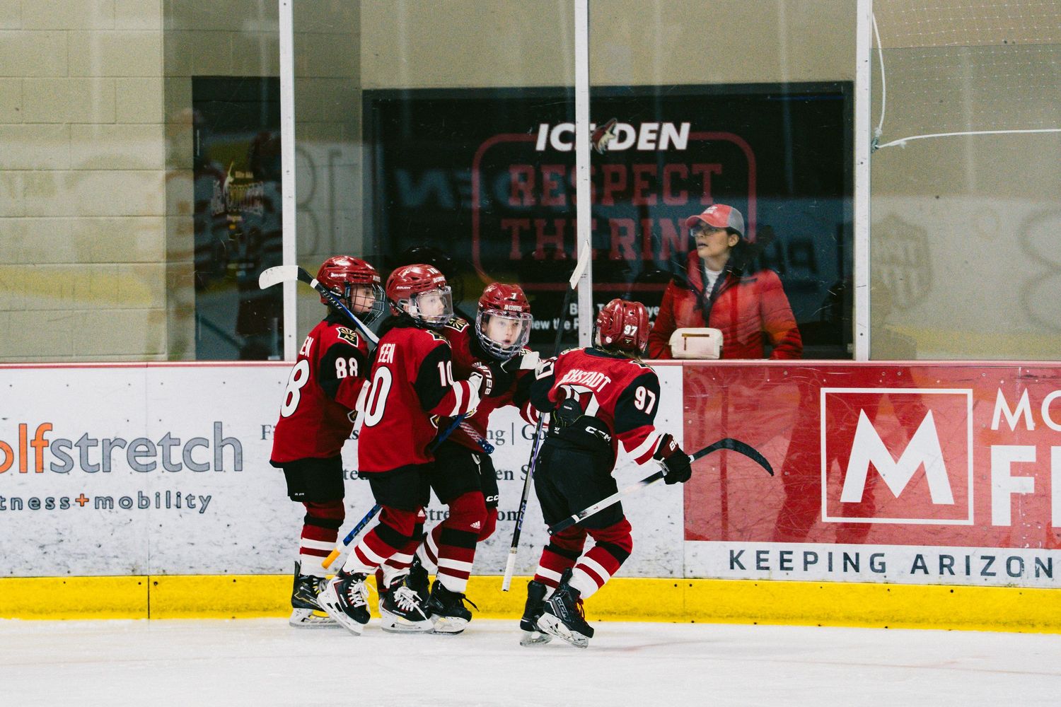 Hockey players in dark uniforms spread across an ice rink during a game or training session.