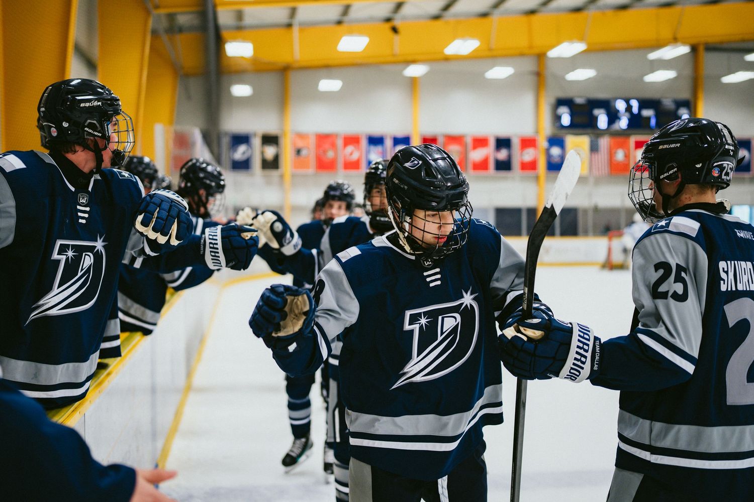 Navy-uniformed ice hockey players exchange fist bumps during a team celebration on the rink.