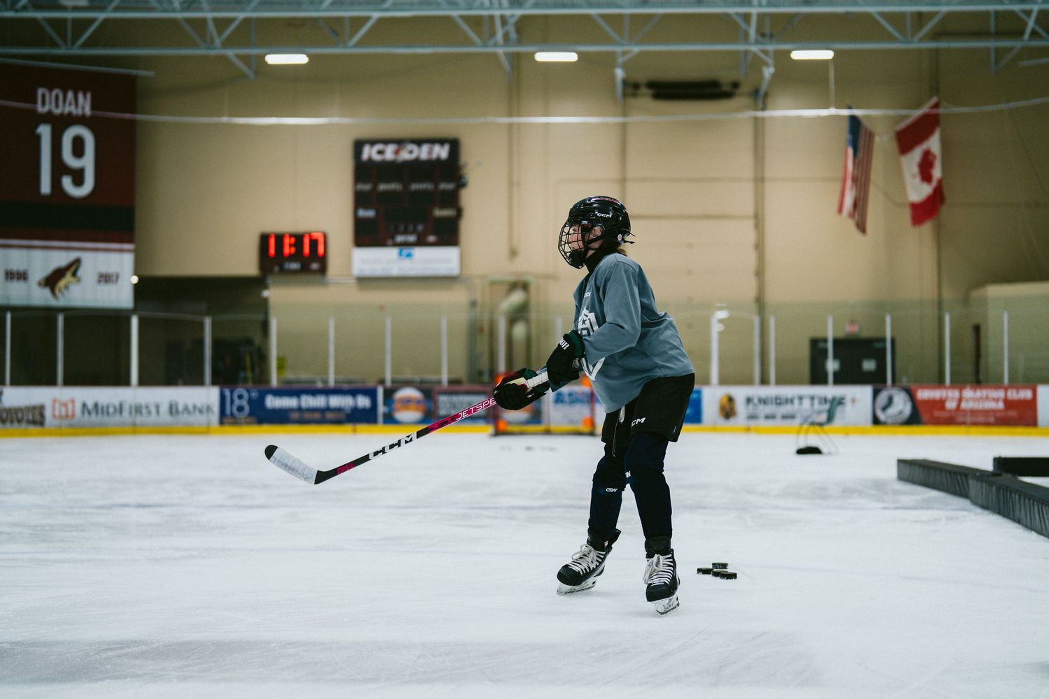 Hockey player skating on indoor ice rink during practice session at Ice Den arena.