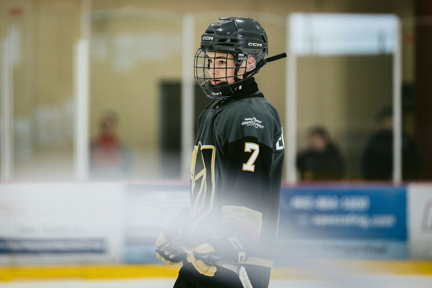 Hockey players in dark uniforms skate across the ice during a game.