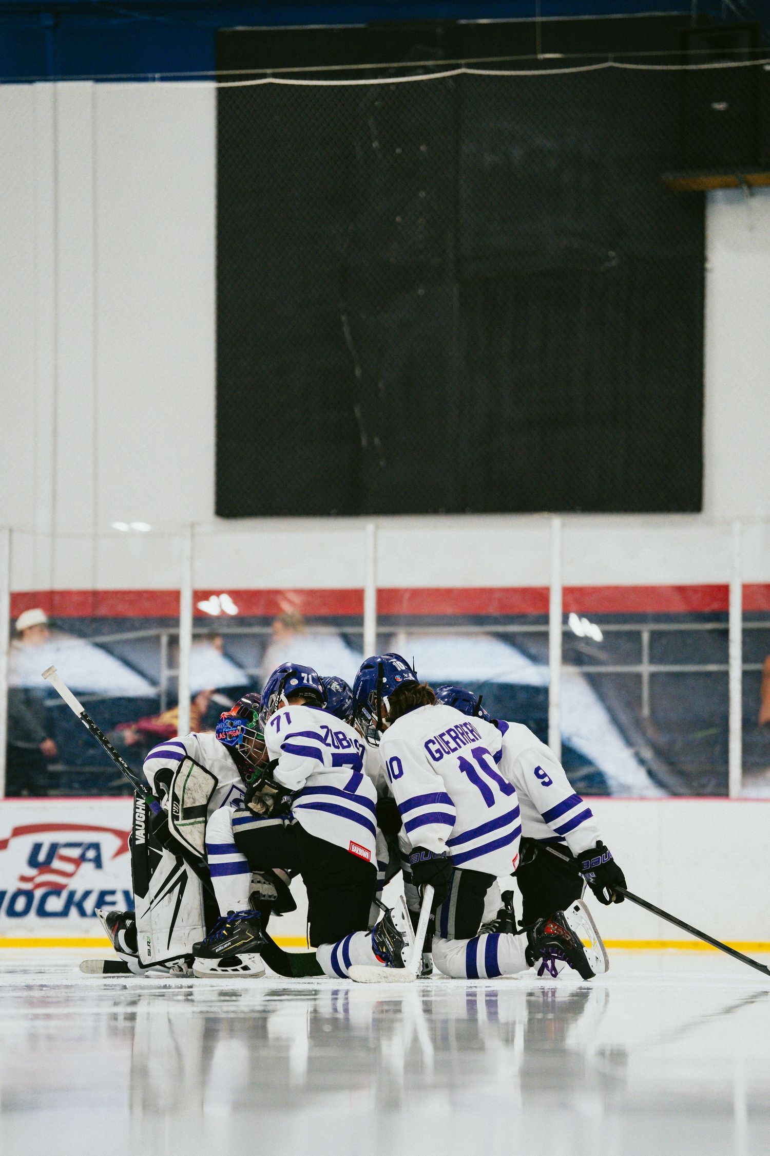 Hockey team huddles together on the ice before a game.