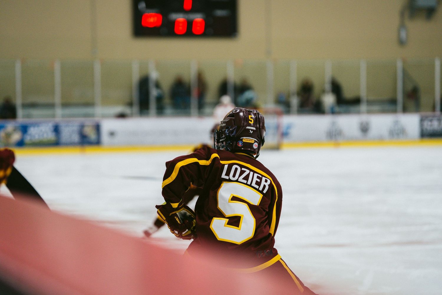 Hockey players in black uniforms spread across the ice rink during gameplay.