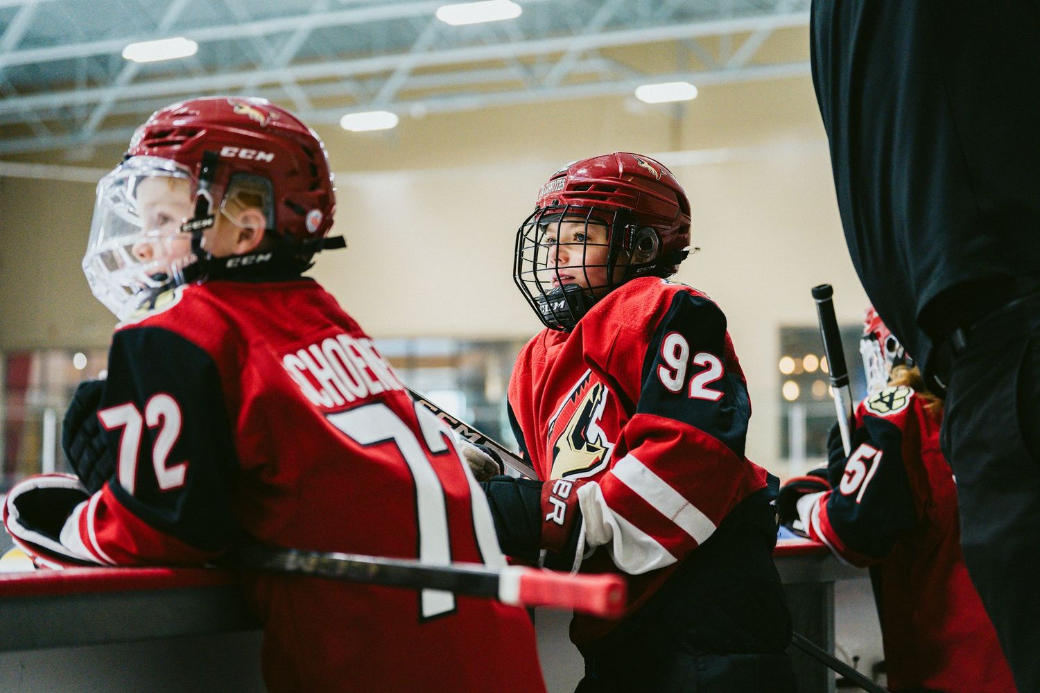 Hockey players in red jerseys huddle together during a game break on the ice.