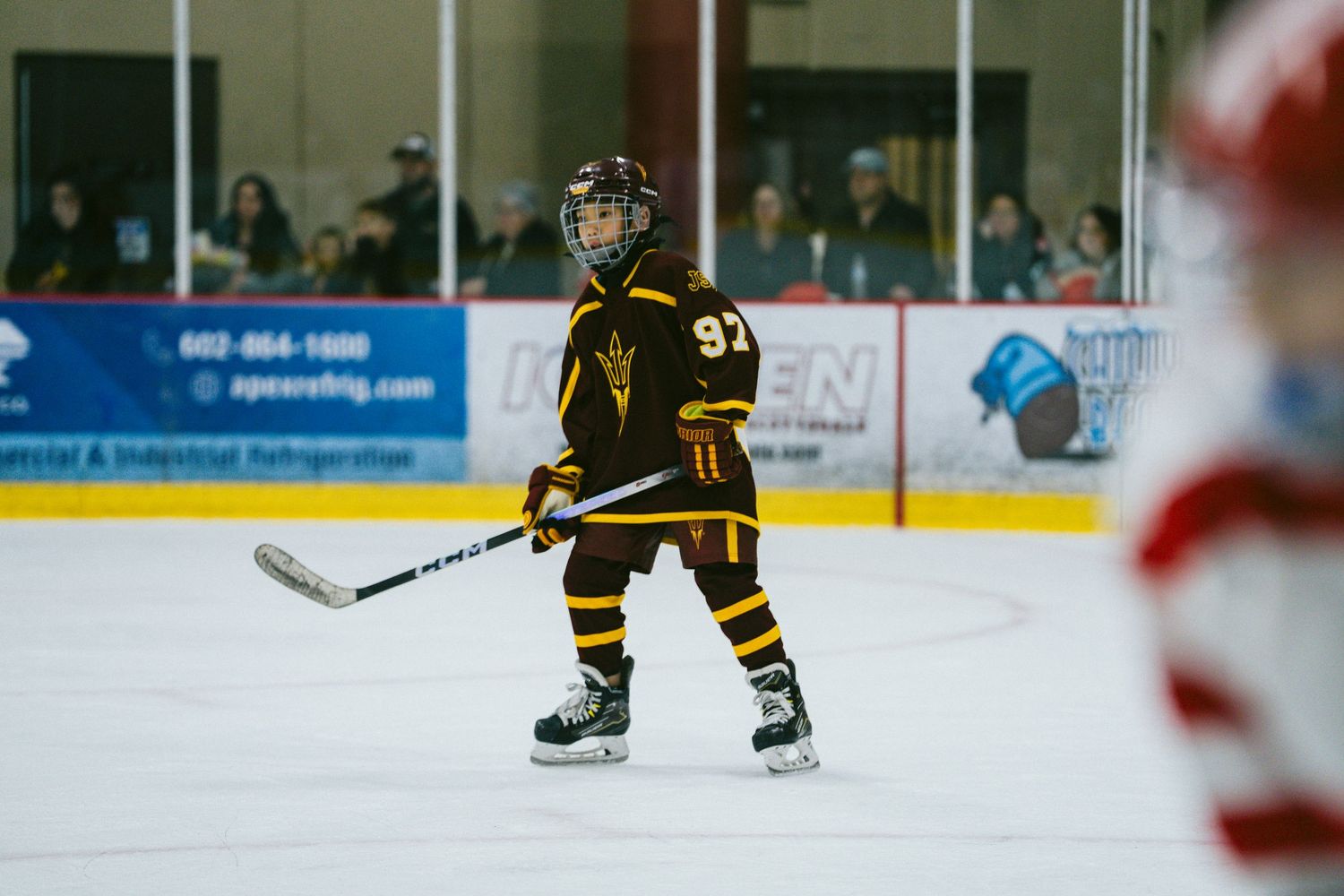 Hockey player in black and gold uniform skates with the puck during competitive play.