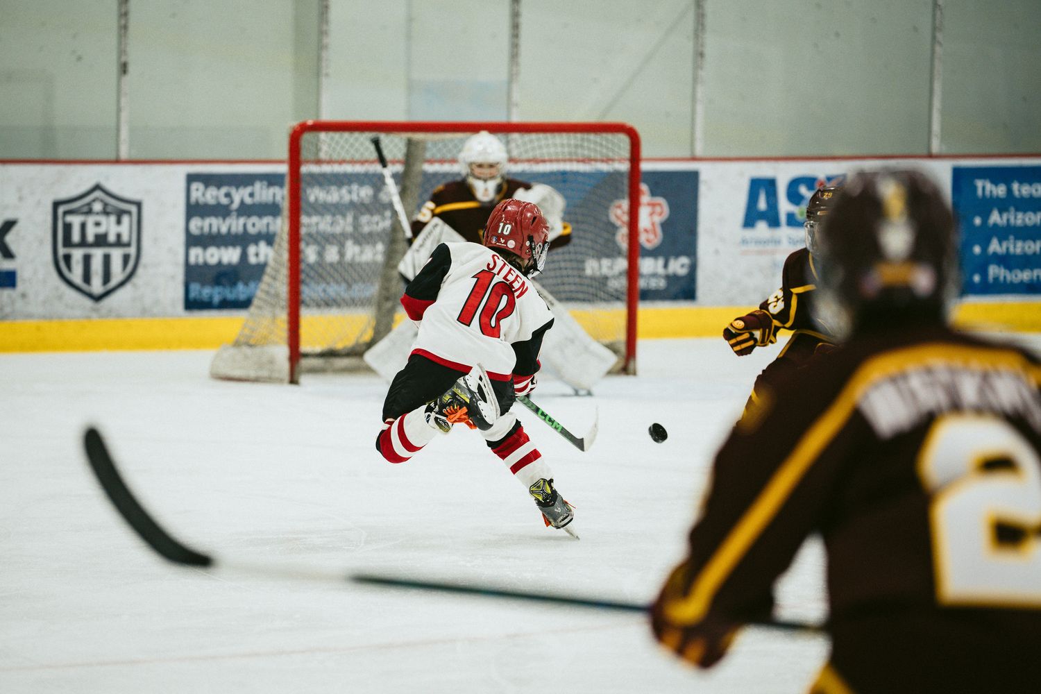 Hockey player takes a shot on goal during competitive game action.