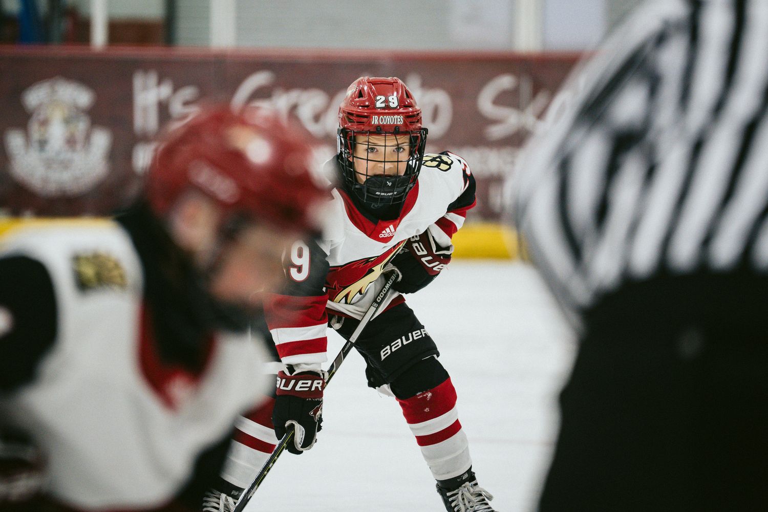 Hockey players in red uniforms compete during an indoor ice rink match.