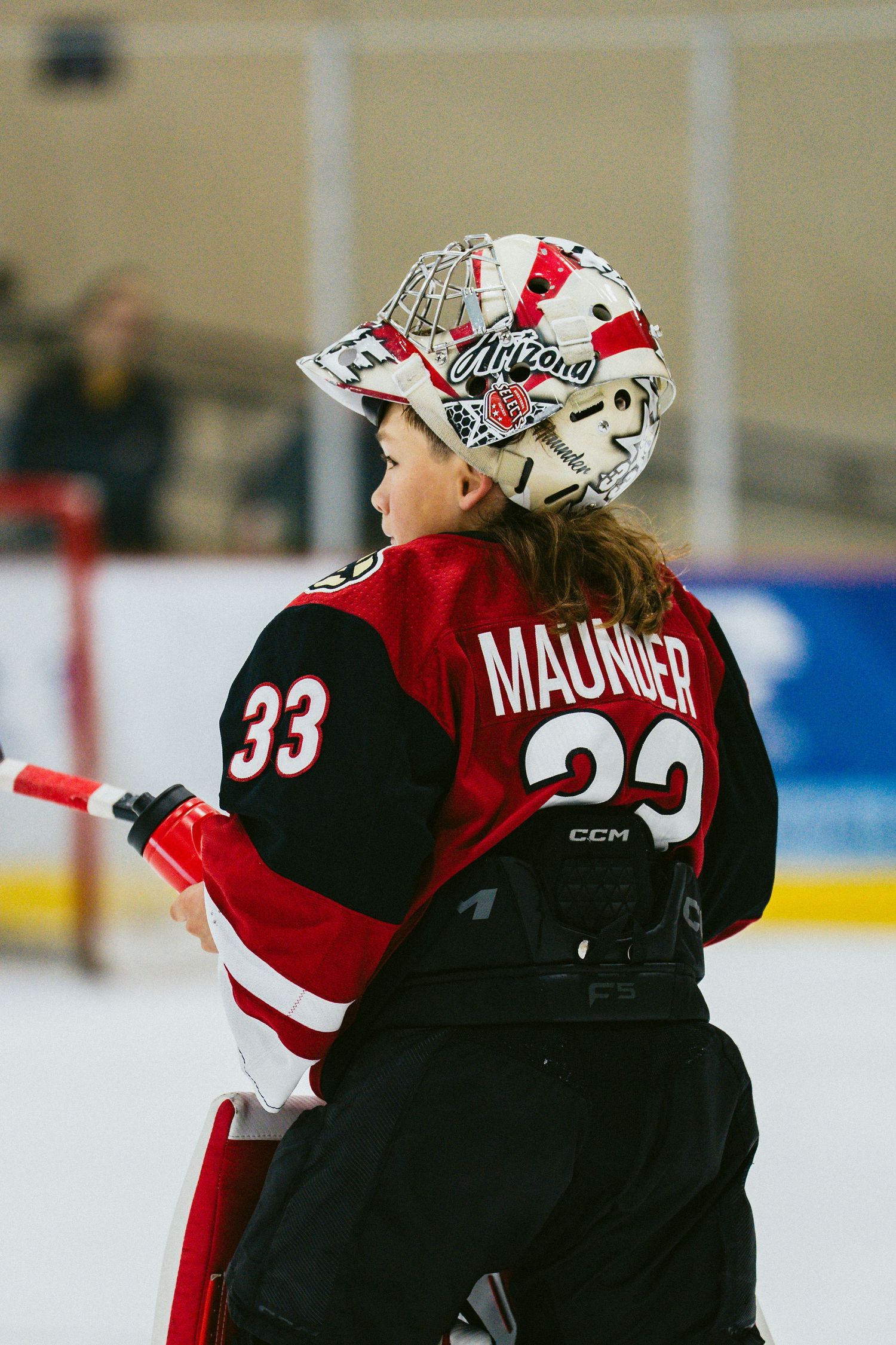 Hockey player wearing jersey number 33 with 'MAUNIER' name plate and decorated goalie mask on ice rink.