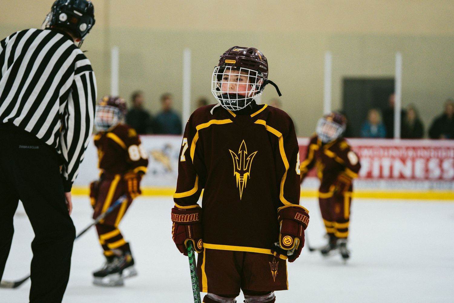 Hockey players in brown uniforms and officials in striped jerseys on the ice during a game.