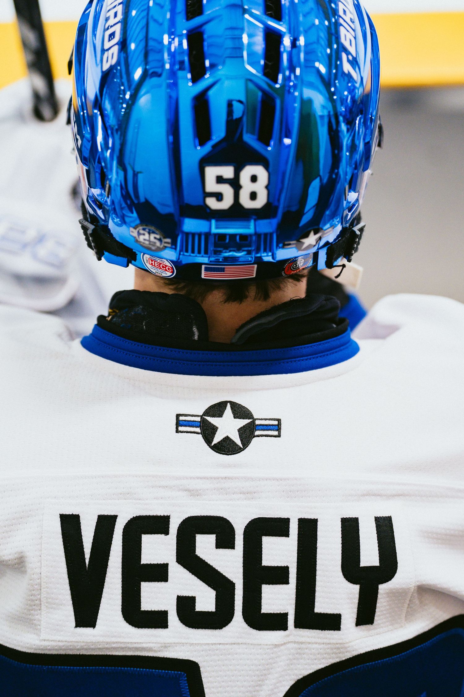 Hockey player Vesely wearing number 58 jersey with a shiny blue helmet viewed from behind.